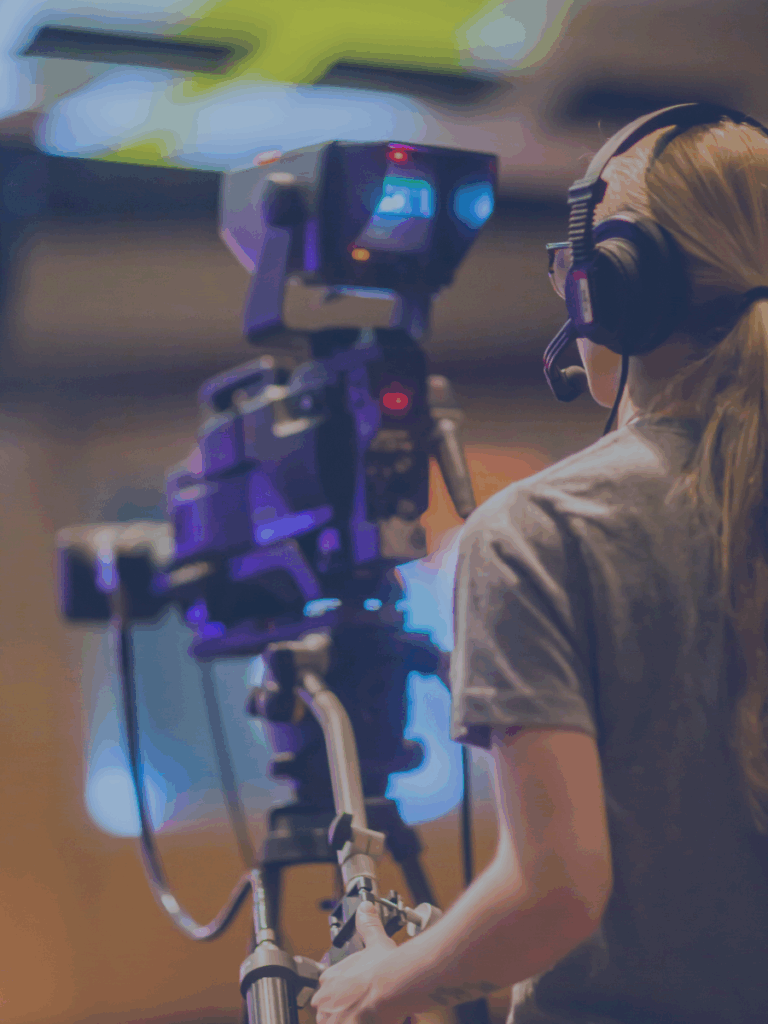 View from behind of human operating a TV broadcast camera.