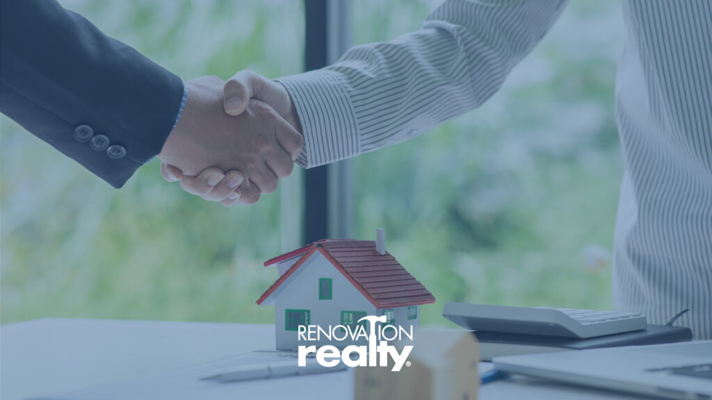 Business handshake over a model house on a desk, symbolizing a real estate agreement, home renovation, or property sale.
