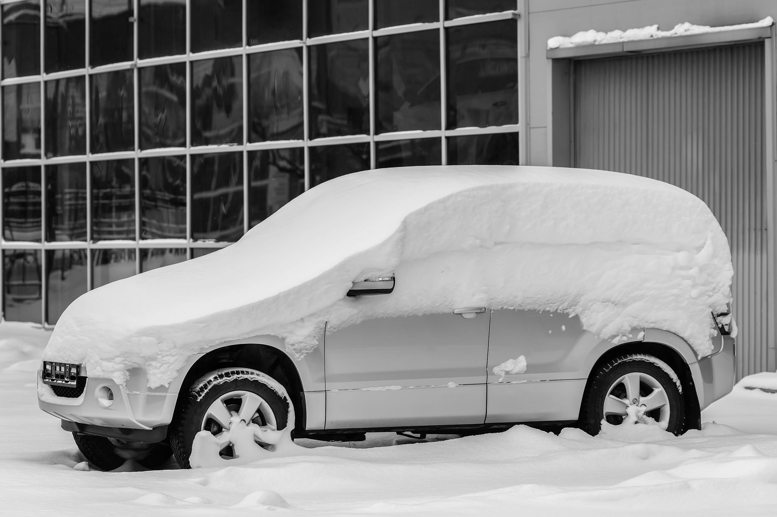 A car covered in a thick layer of snow parked in Russia during winter.