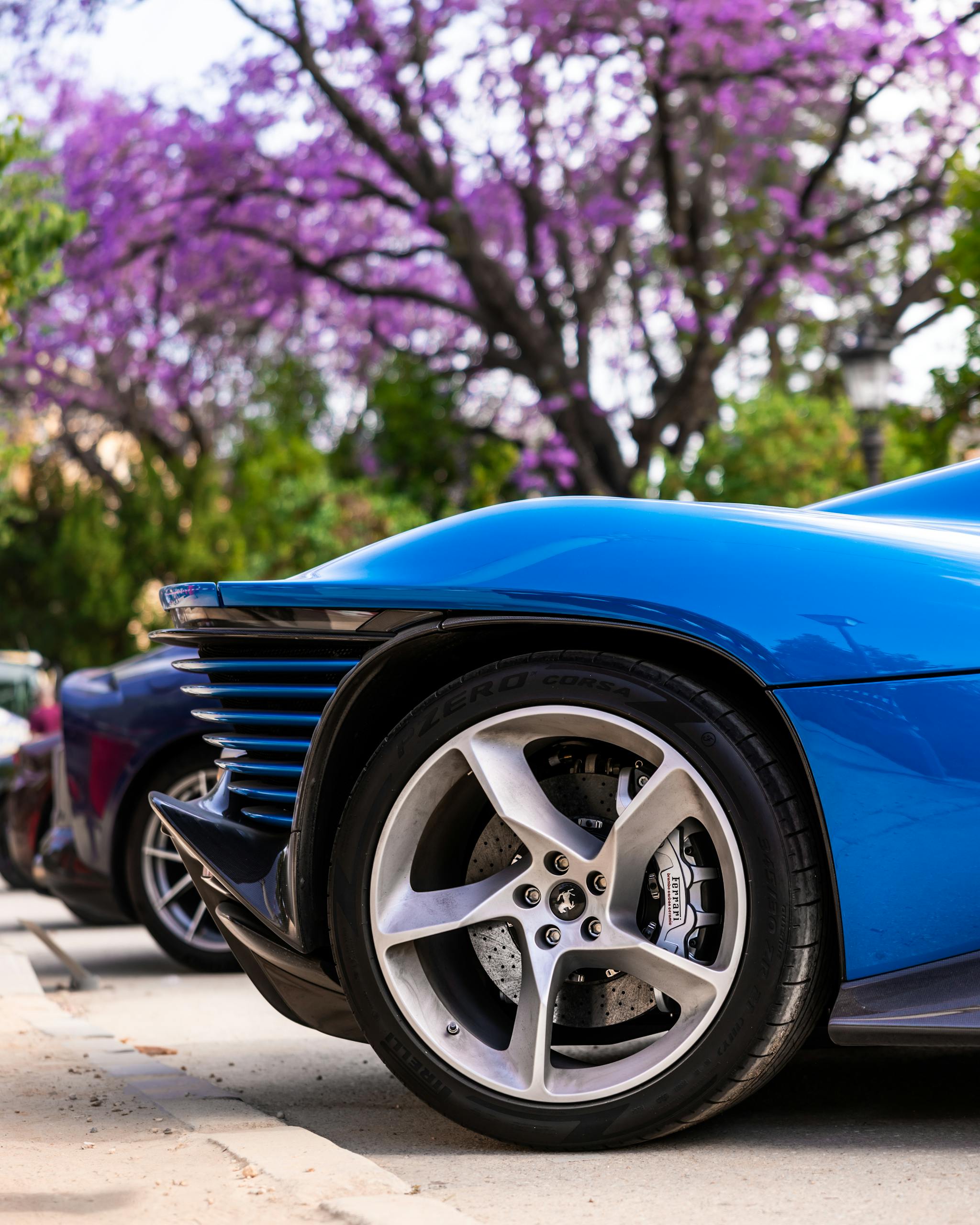 Blue sportscar with trees in full bloom. Vibrant and sleek design.